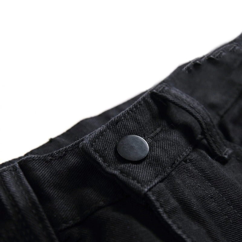 Close-up of the button and waistband detail on black men's biker jeans.