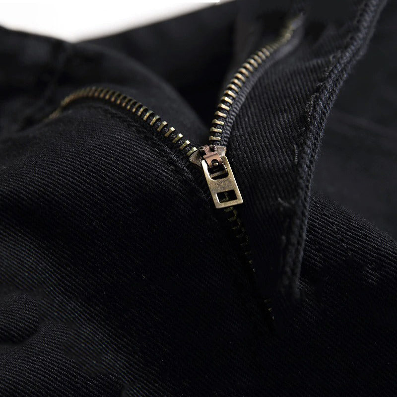 Close-up of a strong zipper on black men's biker jeans, showcasing the sleek denim fabric.