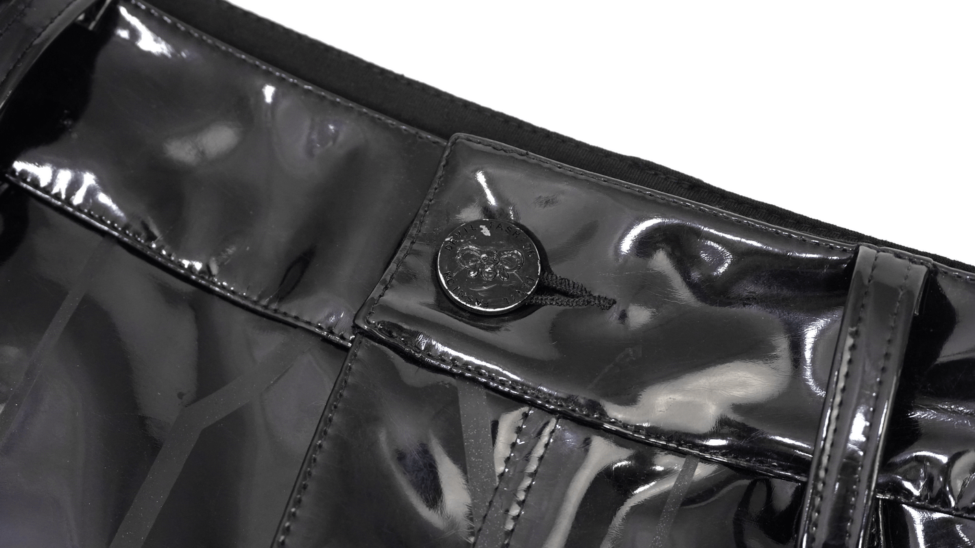 Close-up of sleek black patent leather waistband with stylish button detail on cyberpunk skinny pants.