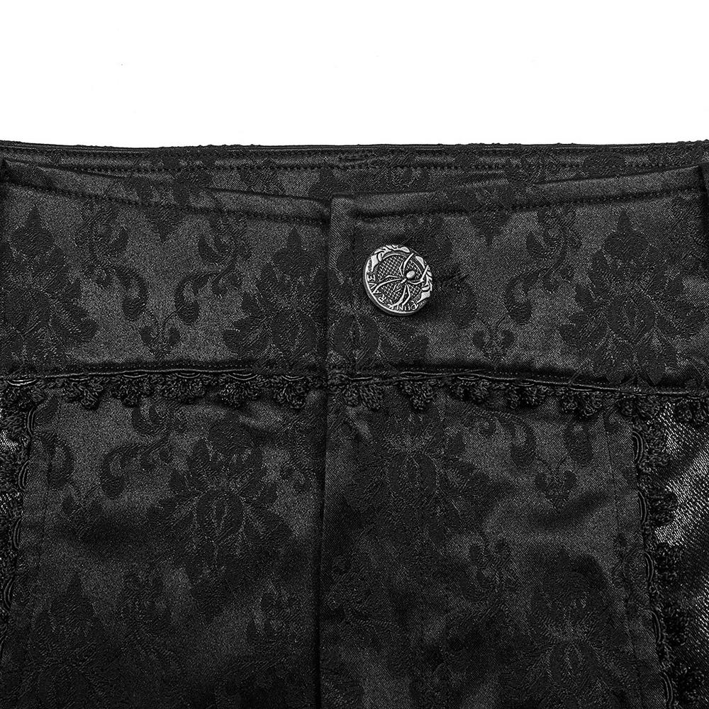 Close-up of black jacquard pants showcasing intricate lace trim and designer button detail in gothic style.
