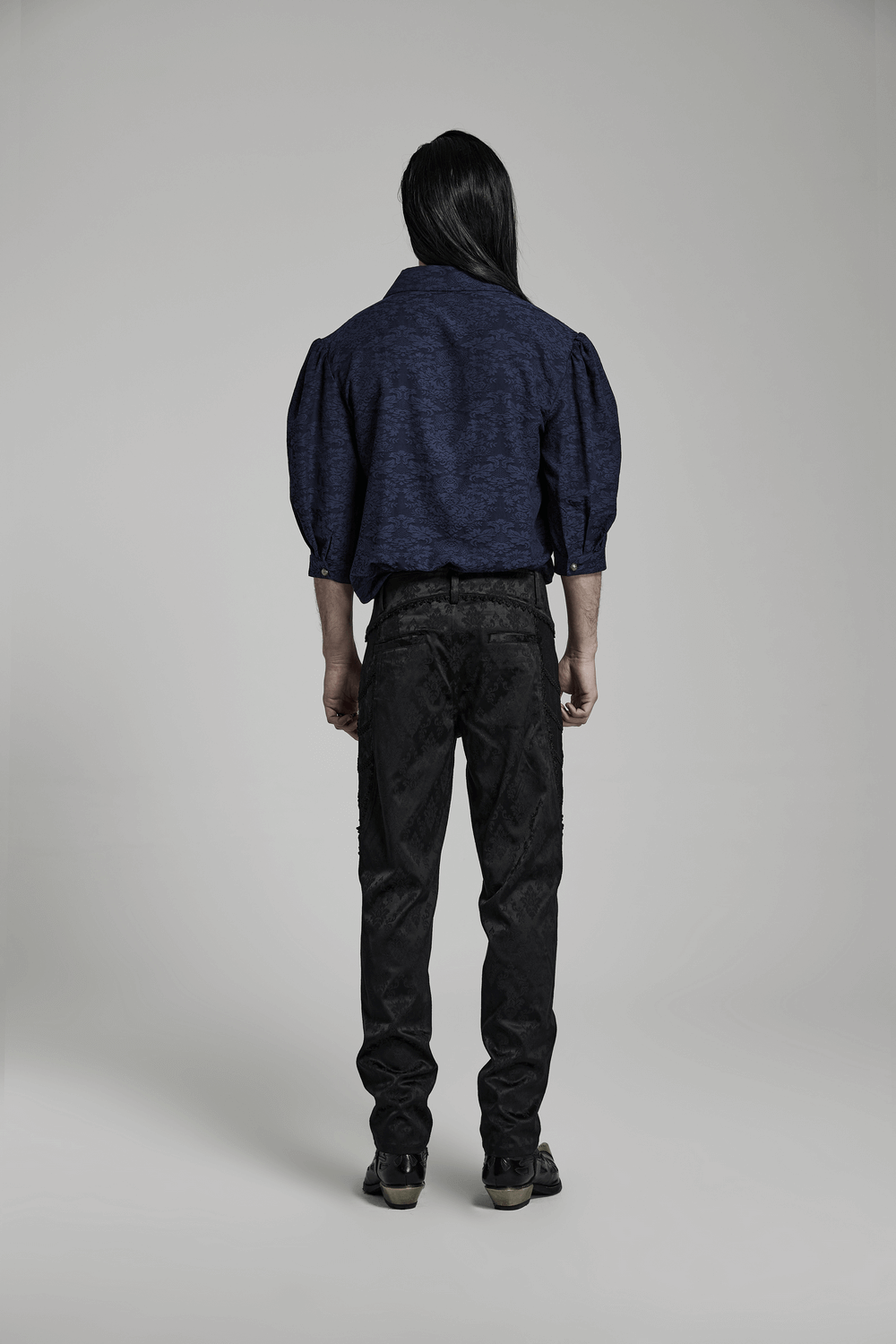 Men's fashion model showcasing gothic black jacquard lace-trim designer trousers from the back.