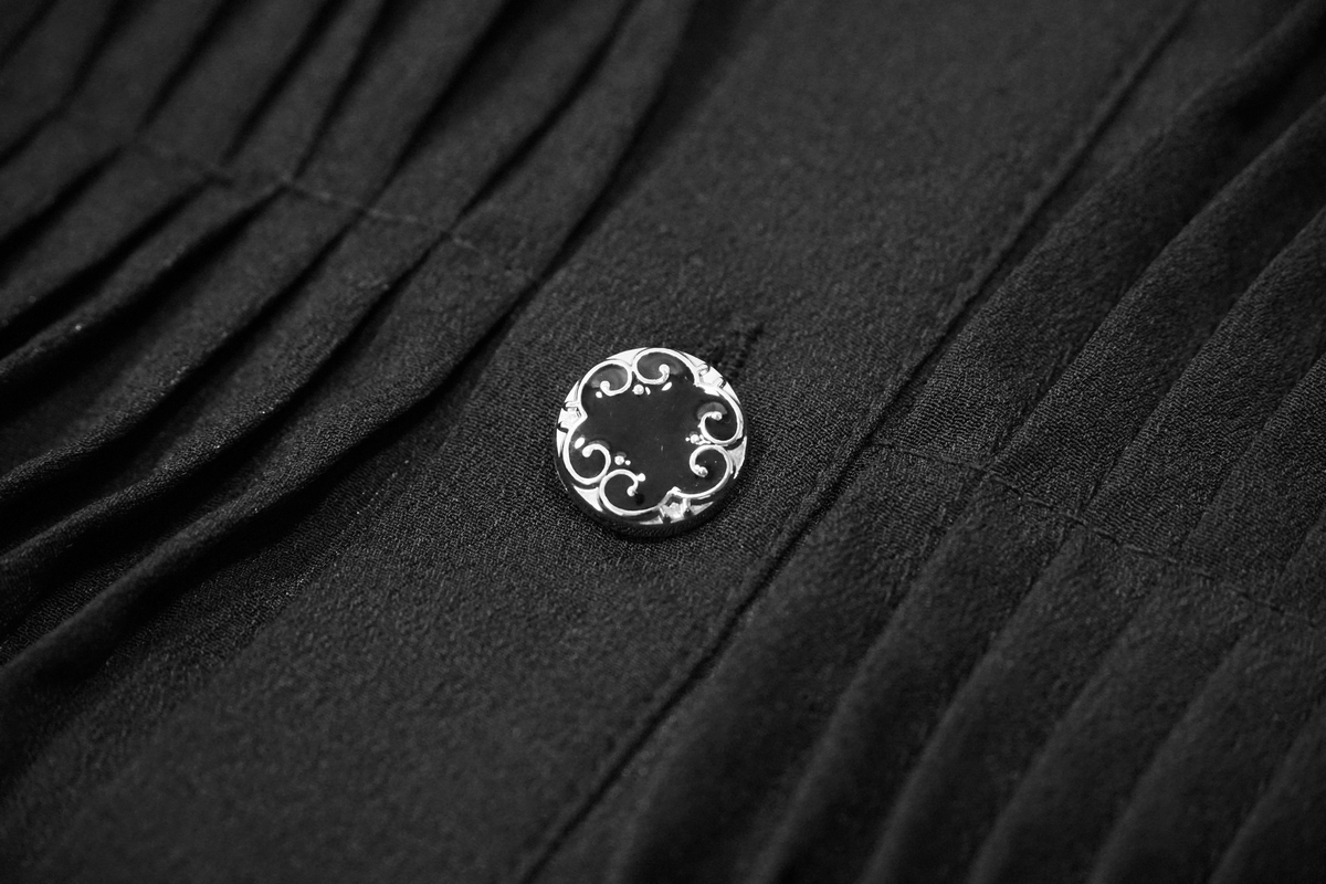 Close-up of a vintage black shirt button with decorative silver design, showcasing gothic style elegance.