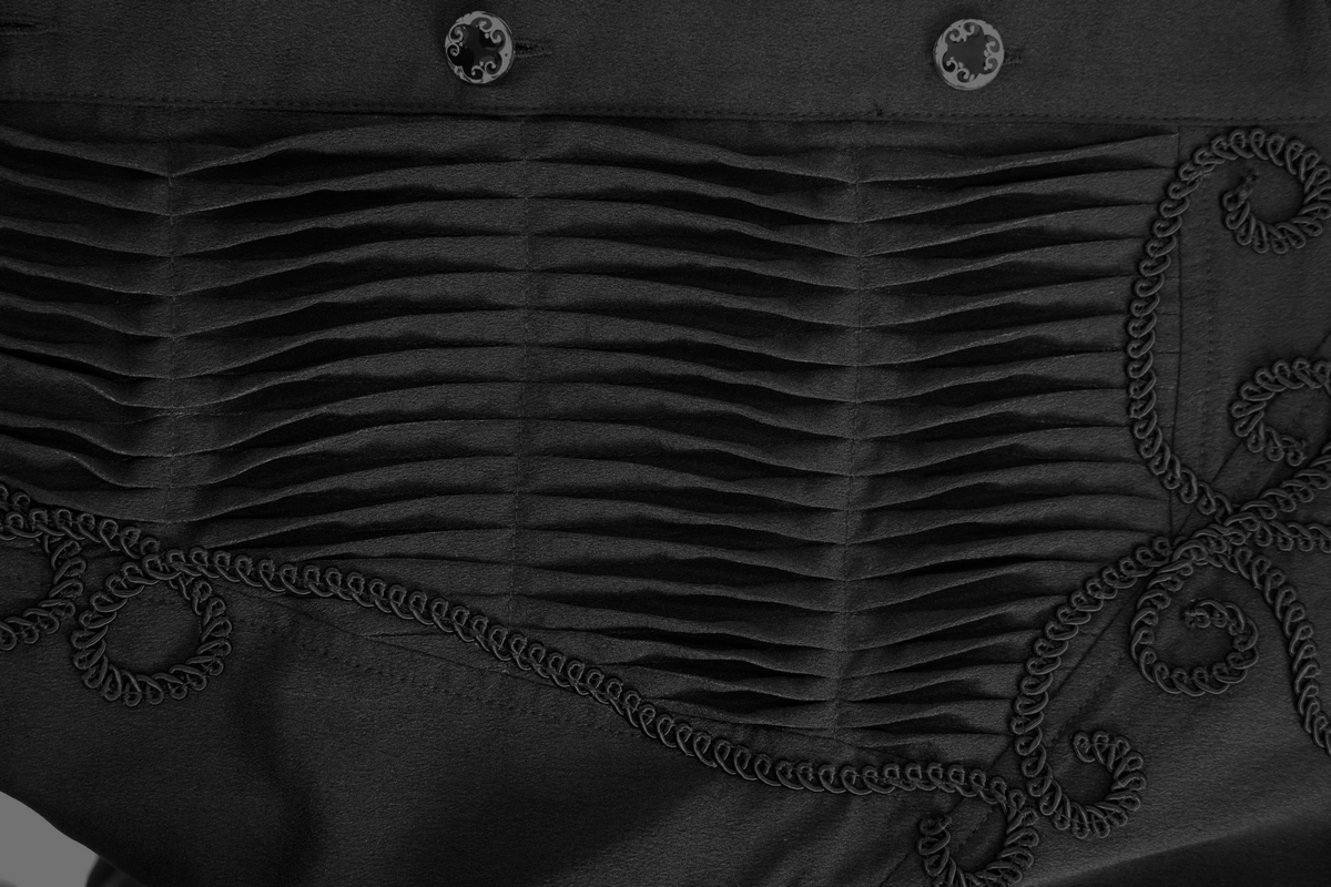 Close-up of men's black gothic shirt featuring pleated design and intricate lace detailing on collar and cuffs.