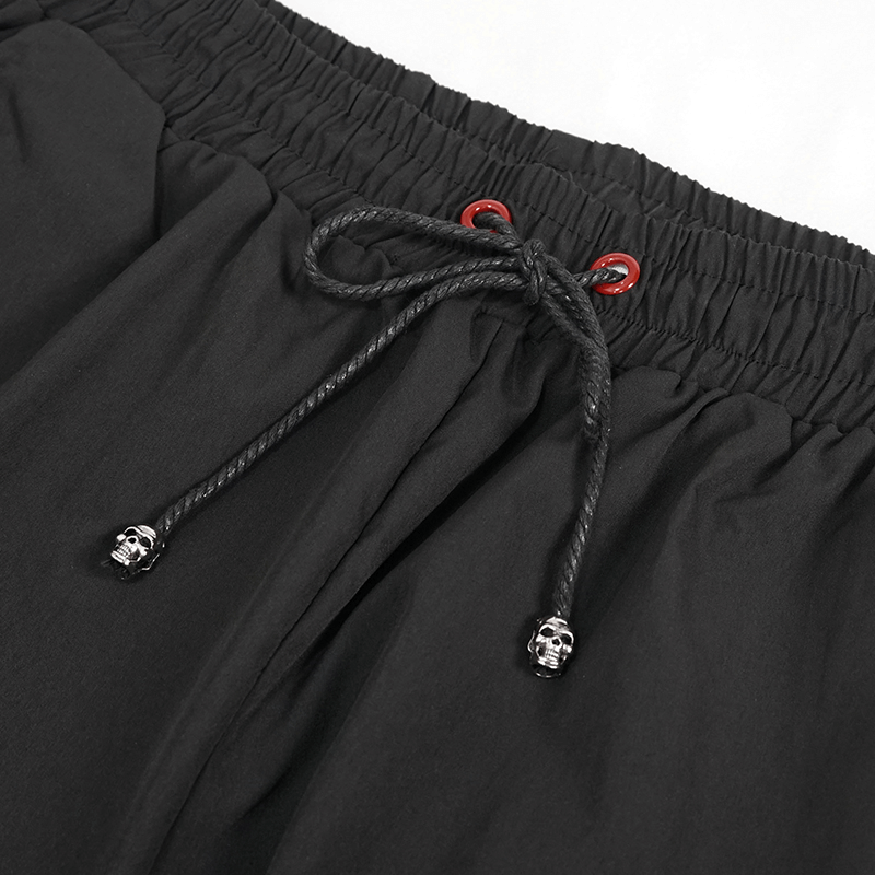 Close-up of black punk cargo trousers' waistband with red accents and skull drawstring details.