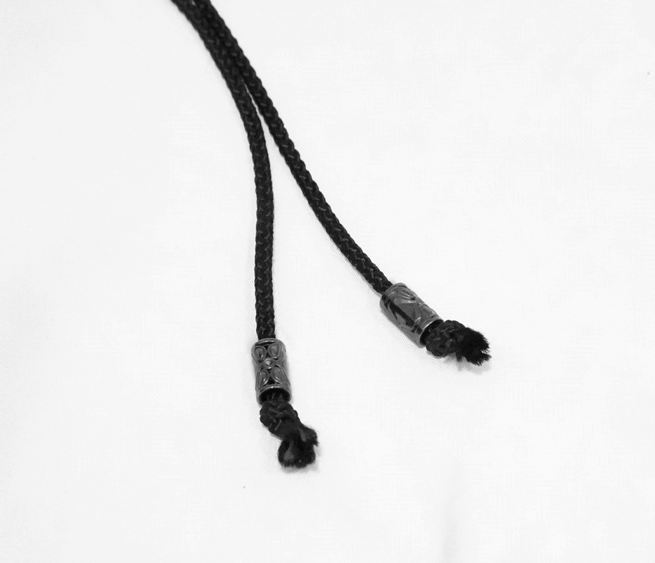 Close-up of black braided lacing with decorative ends for gothic-style jackets and accessories.