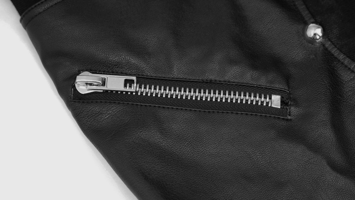 Close-up of men's black faux leather trousers featuring stylish zipper detail and silver accents.