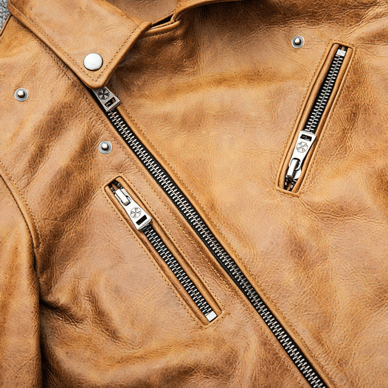 Close-up of men's genuine leather motorcycle jacket in yellow brown with silver zippers and thick turn collar.