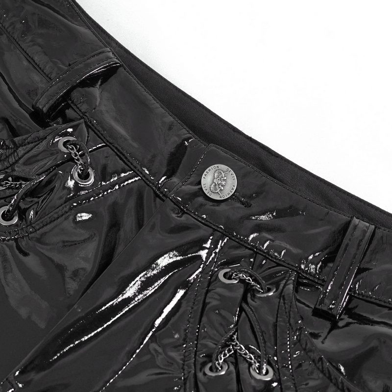 Close-up of glossy black leather lace-up trousers featuring bold chains and stylish button detail.