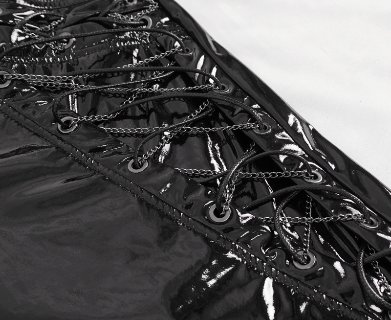 Close-up of glossy black leather lace-up detail with chains on men's fashion trousers.