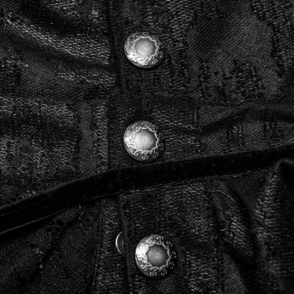 Close-up of Gothic snap buttons on a men's black cape, showcasing intricate silver detailing and textured fabric.