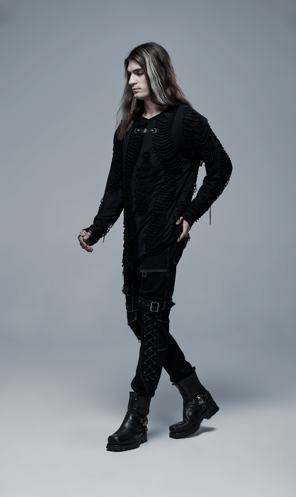 Model showcasing men's gothic buckled cargo pants with strap accents and layered black top in an urban setting.