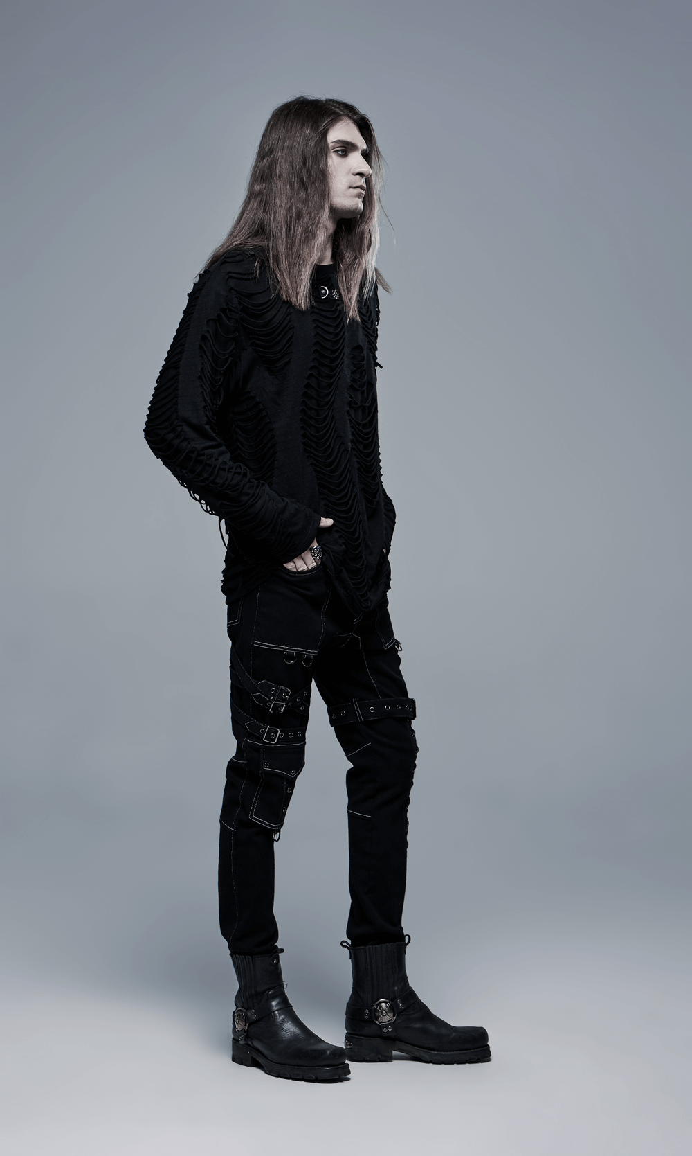 Trendy model wearing Men's Gothic Buckled Cargo Pants with strap details and stylish black sweater.