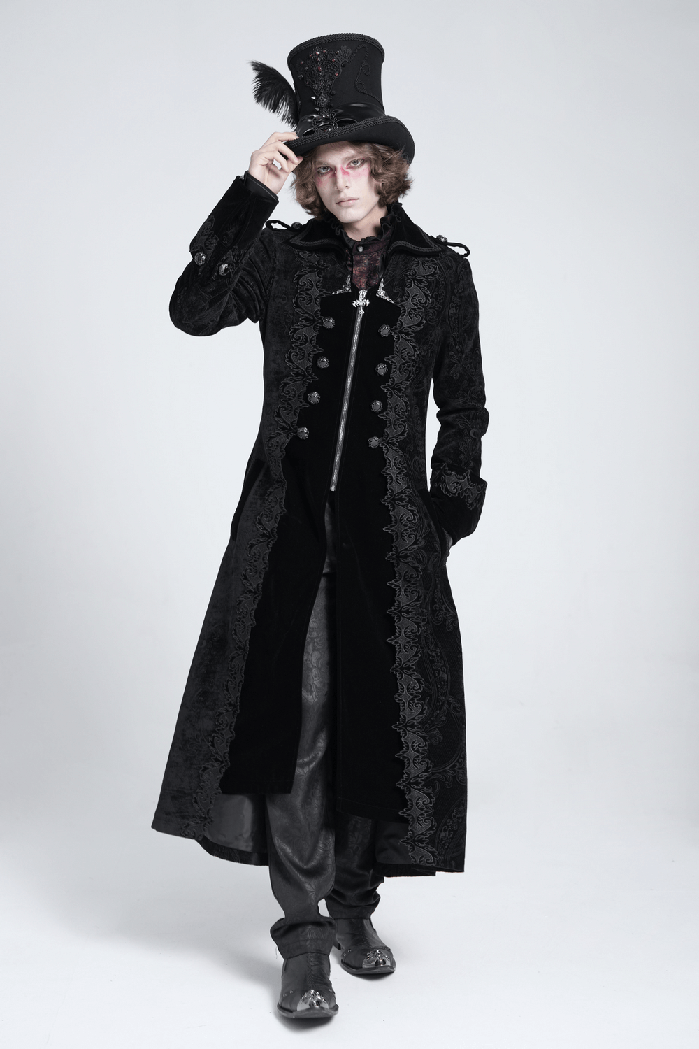 Men's Gothic long velvet coat with brocade trim, styled with a black top hat and striking accessories.