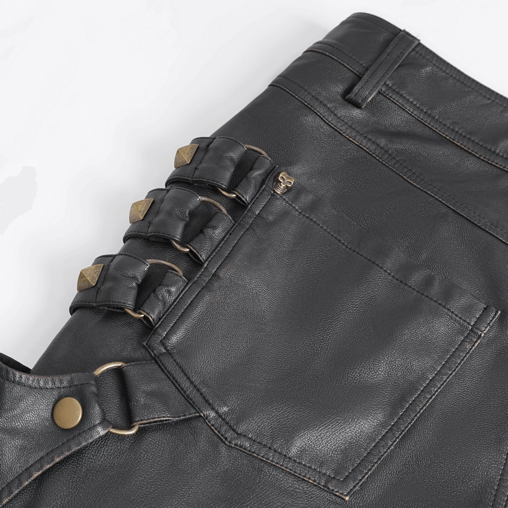 Close-up of black faux leather pants showcasing silver studs and buckle detailing for a bold punk gothic style.