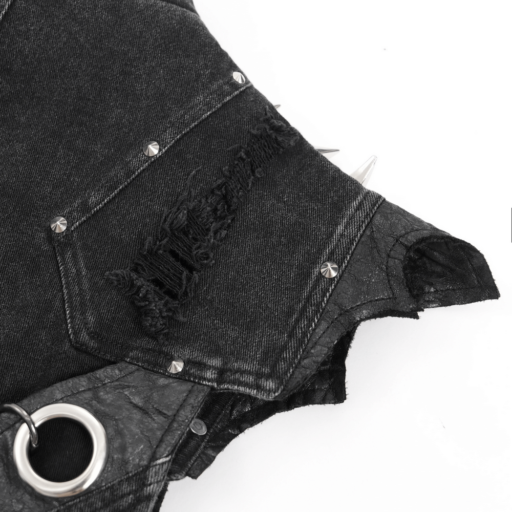 Close-up of a black denim vest with metal studs, distressed details, and chain ring embellishments for a gothic punk style.