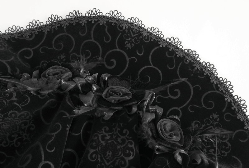 Close-up of intricate lace and floral detailing on a black velvet cloak, showcasing gothic elegance and craftsmanship.
