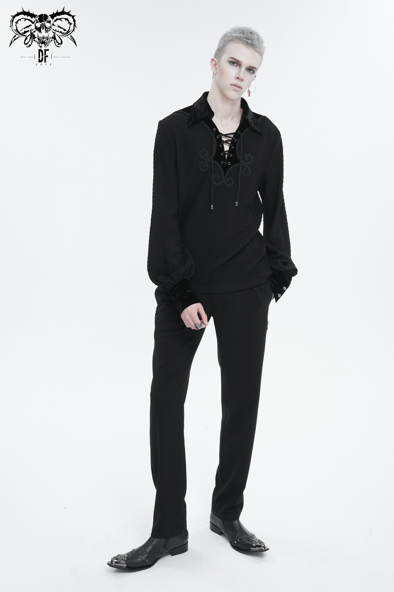 Stylish man in a black gothic strappy puff-sleeved shirt with lace-up detailing and loose fit trousers.