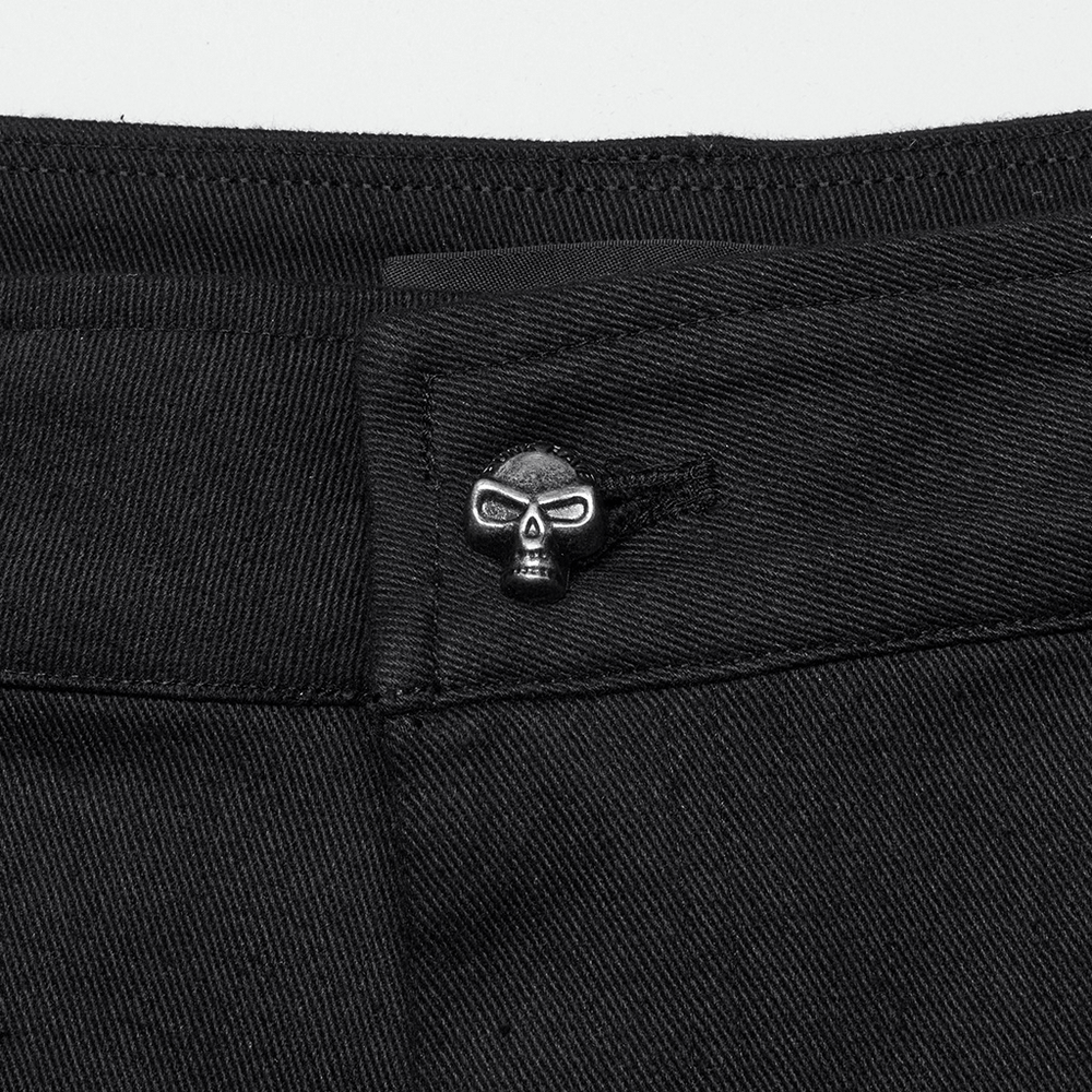 Close-up of black twill pants featuring a skull button accent, showcasing edgy punk style details.