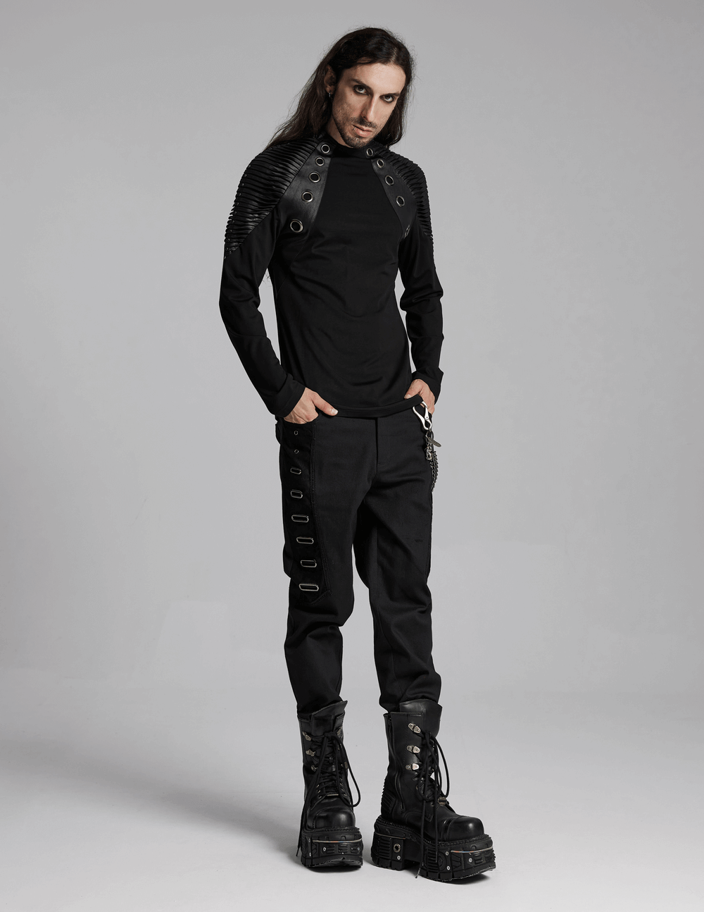 Stylish man in black gothic twill pants with eyelet details and oversized boots, showcasing punk streetwear fashion.