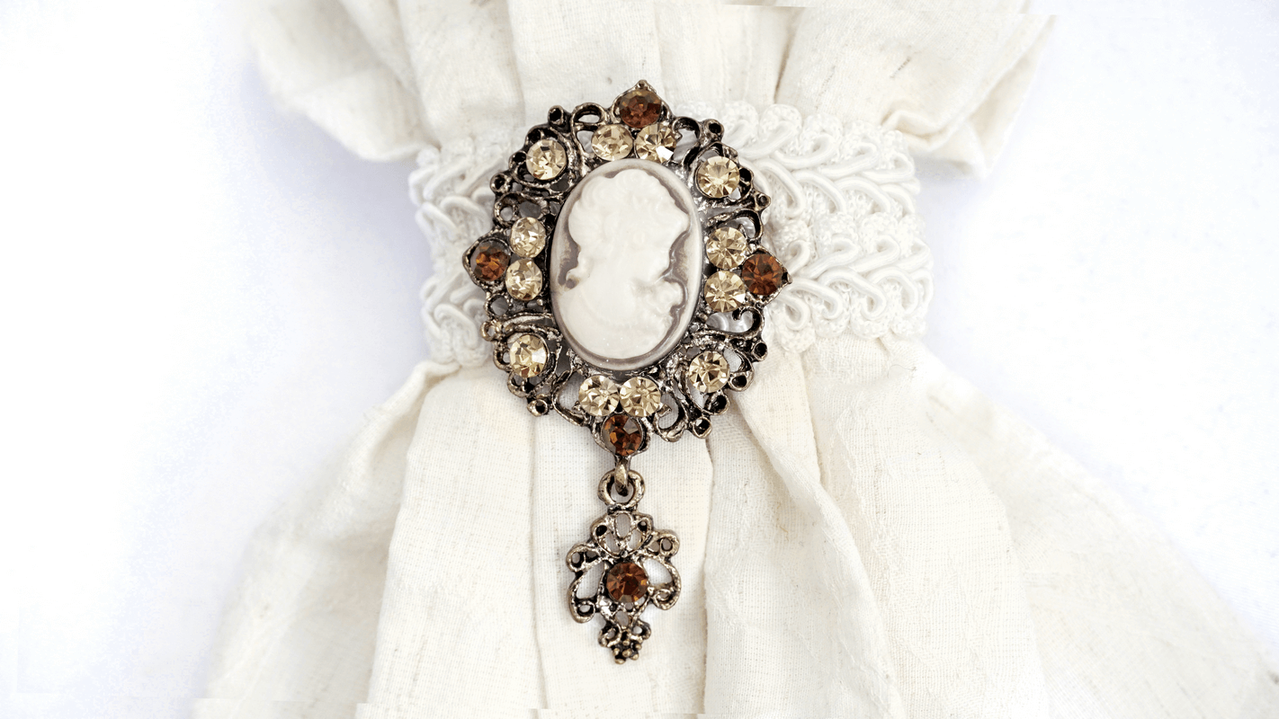 Elegant vintage brooch with intricate detailing, set on a white fabric, perfect for gothic-style accessories.