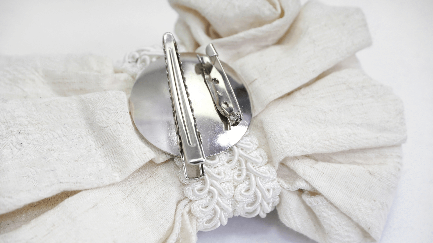 Close-up of the back of a white gothic tie showcasing its vintage brooch and secure clasp.