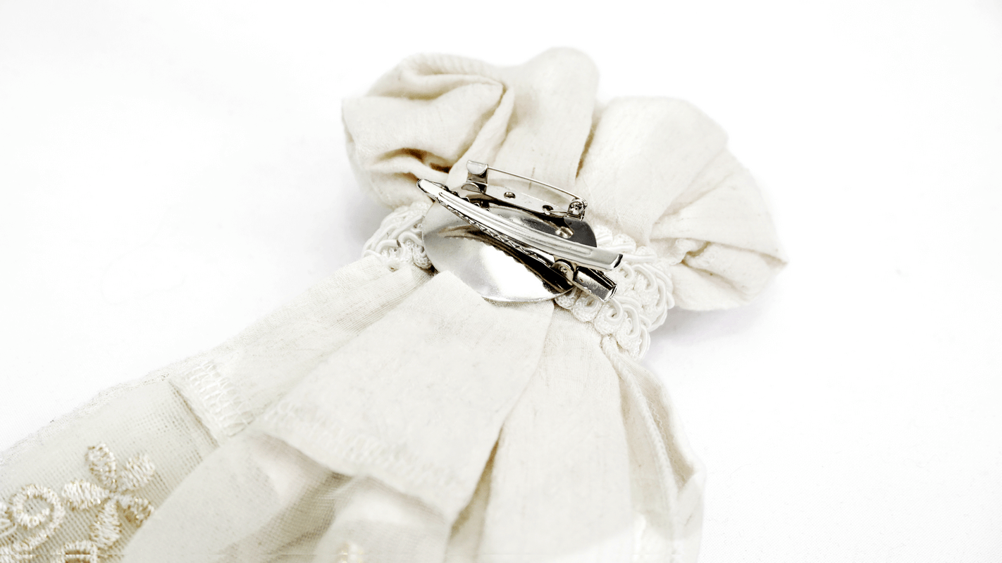 Close-up of the vintage white cotton tie's elegant fabric and retro brooch detail, perfect for gothic fashion.