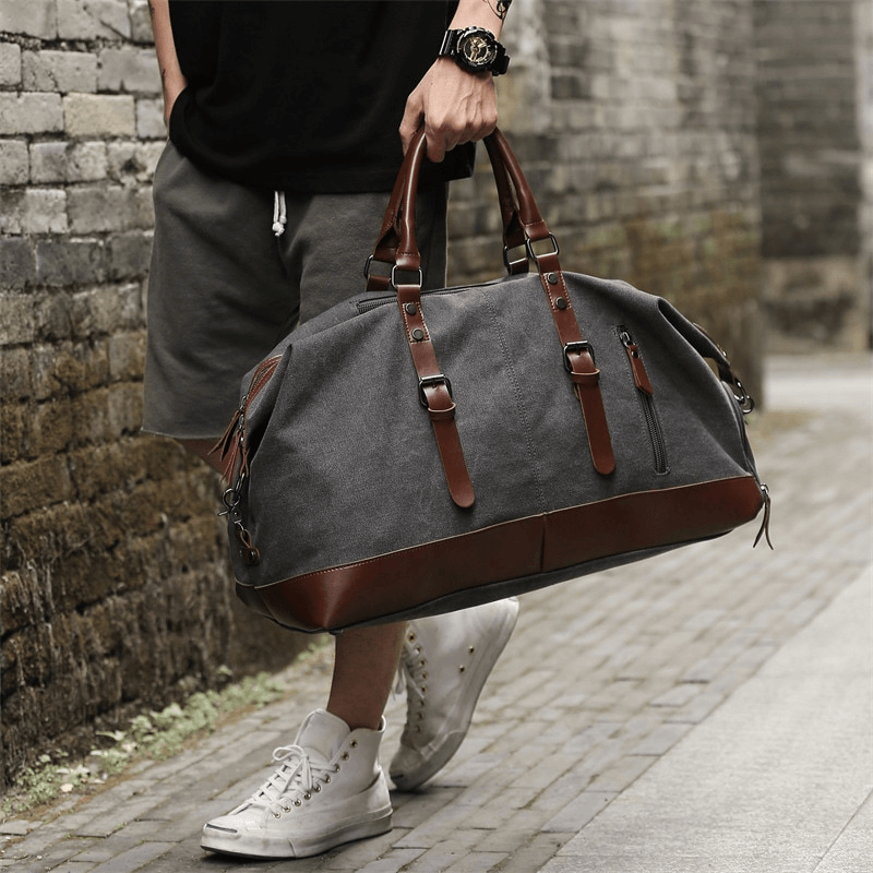 Stylish men's large capacity travel duffel bag in grey with brown straps, ideal for casual travel and organization.