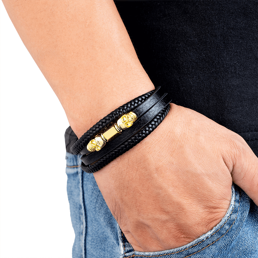 Close-up of man wearing men's multilayer faux leather bracelet with gold clasp, showcasing edgy gothic style.