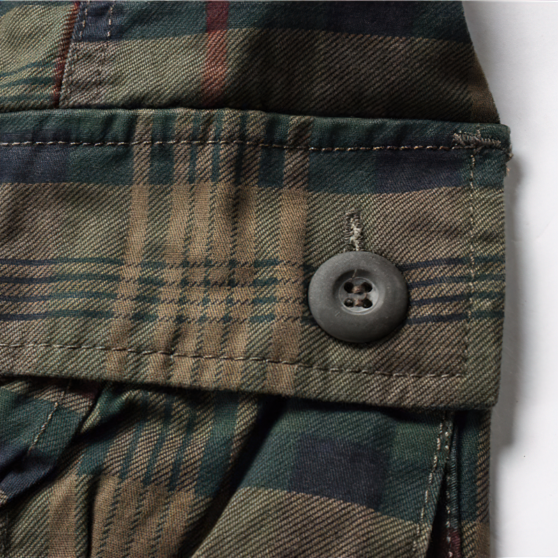 Close-up of plaid fabric and button detail on men's casual cargo shorts, showcasing style and quality craftsmanship.