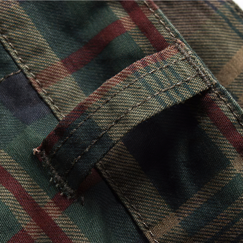 Close-up of green and red plaid fabric with stitching detail from men's cargo shorts.