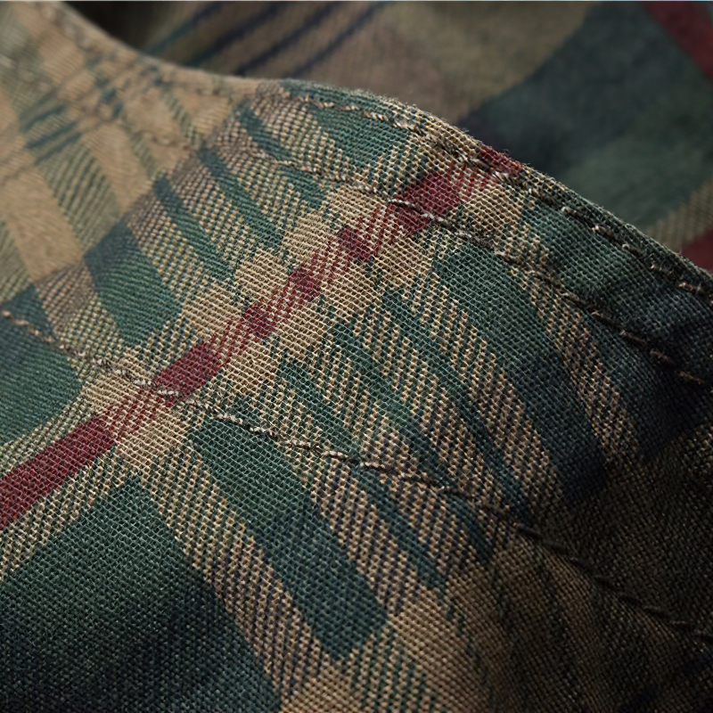 Close-up of green plaid fabric showing intricate stitching, perfect for men's cargo shorts in a casual military style.