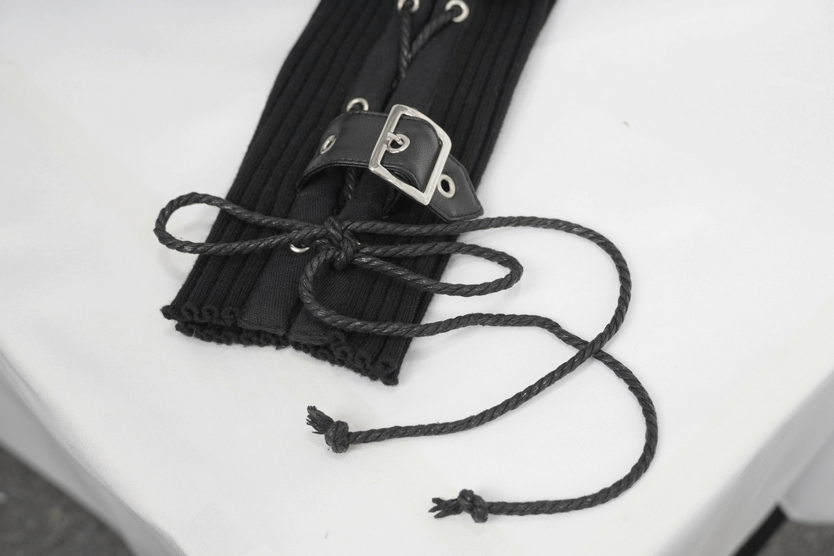 Close-up of black lace-up detail and buckle on a punk-style hoodie sleeve, showcasing unique design features.