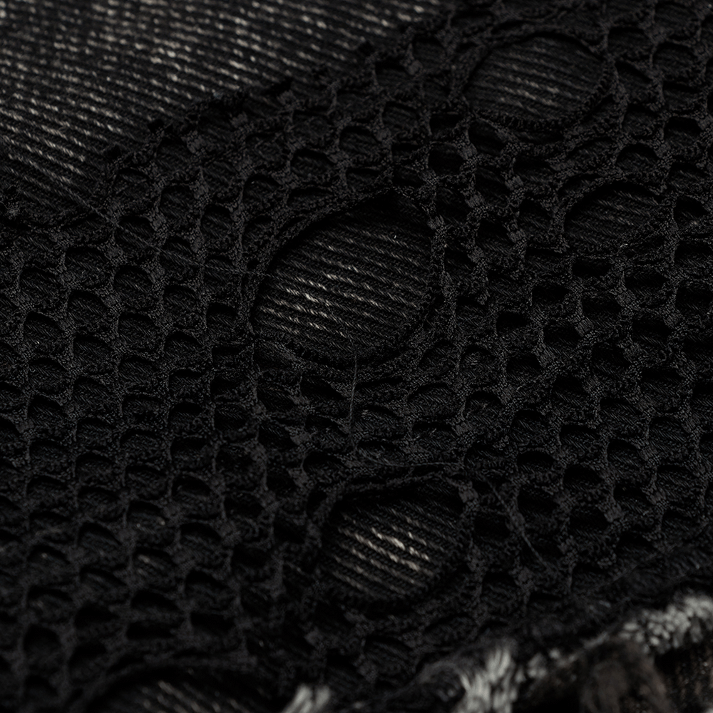 Close-up of black coarse twill denim with broken mesh detail, showcasing punk vest texture and style.
