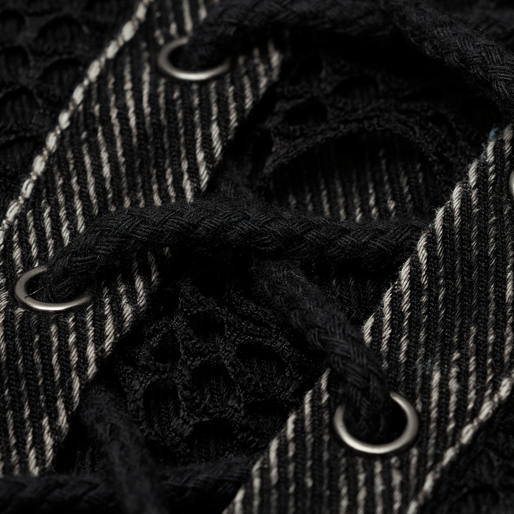 Close-up of black denim vest detailing with lace-up design and metal grommets, showcasing punk style elements.