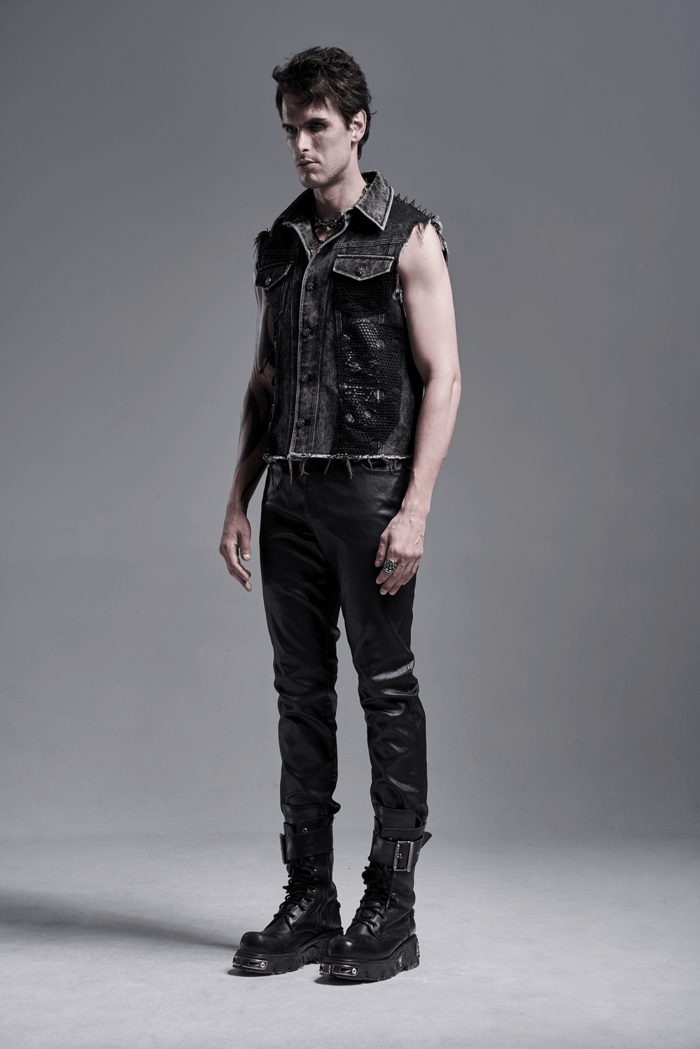 Model showcasing men's punk denim vest with rivets and patches, exuding edgy street style and rebel attitude.