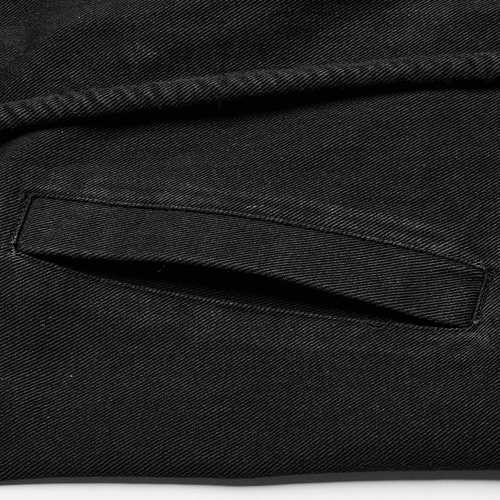 Close-up of the pocket detail on a black distressed denim vest for a punk gothic look.