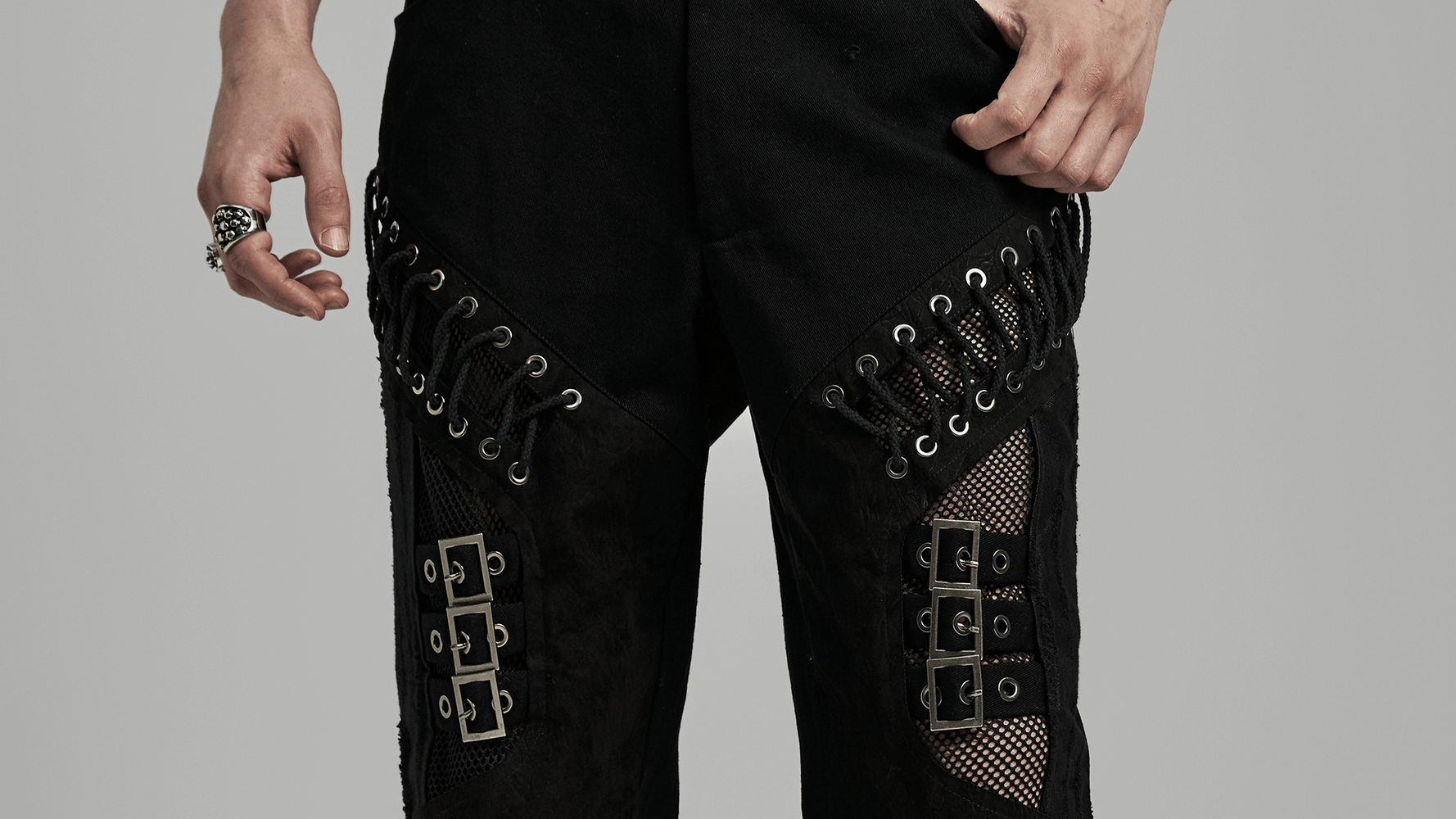 Men's punk style black pants featuring laced eyelets and mesh inlays for a bold, edgy look.