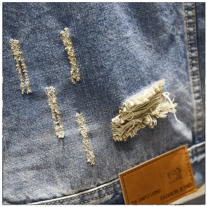 Close-up of stylish ripped denim jacket fabric showcasing unique abrasions and vintage design details.