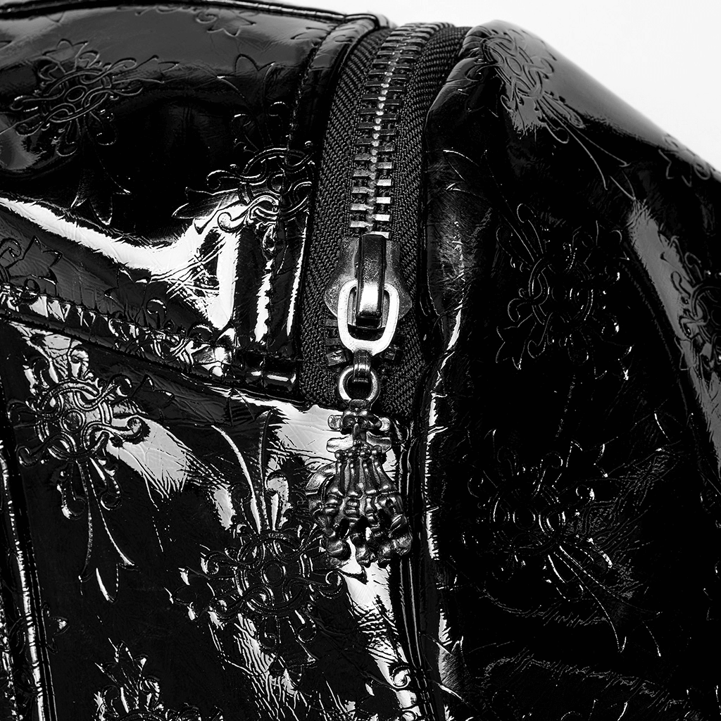 Close-up of a shiny black patent leather bag with a decorative zipper and floral embossing detail.
