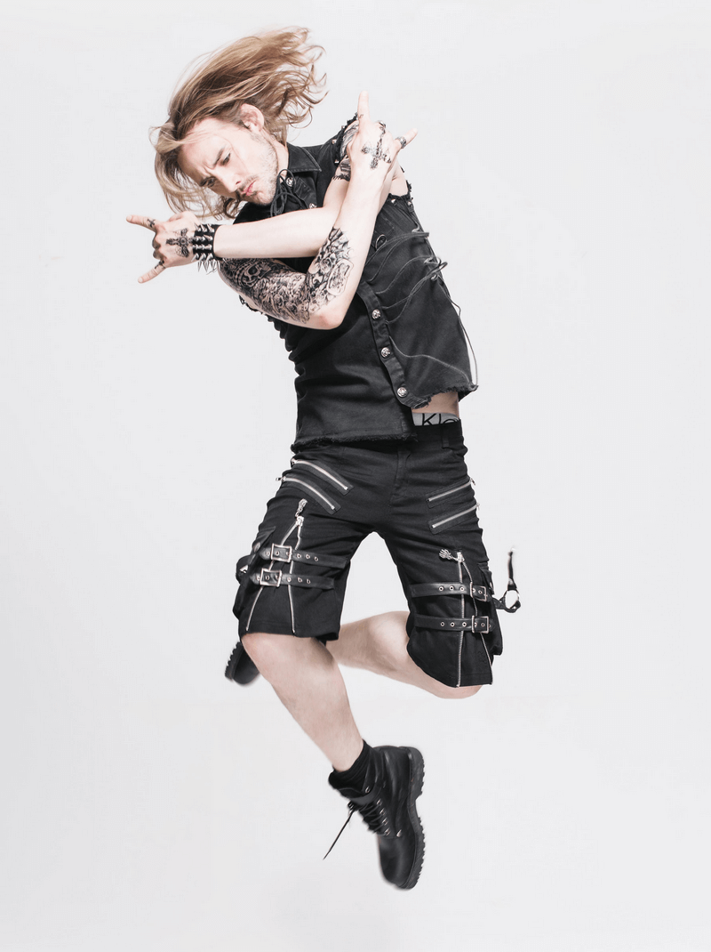 Man in gothic sleeveless shirt with decorative buttons, showcasing a stylish jump in edgy black shorts.
