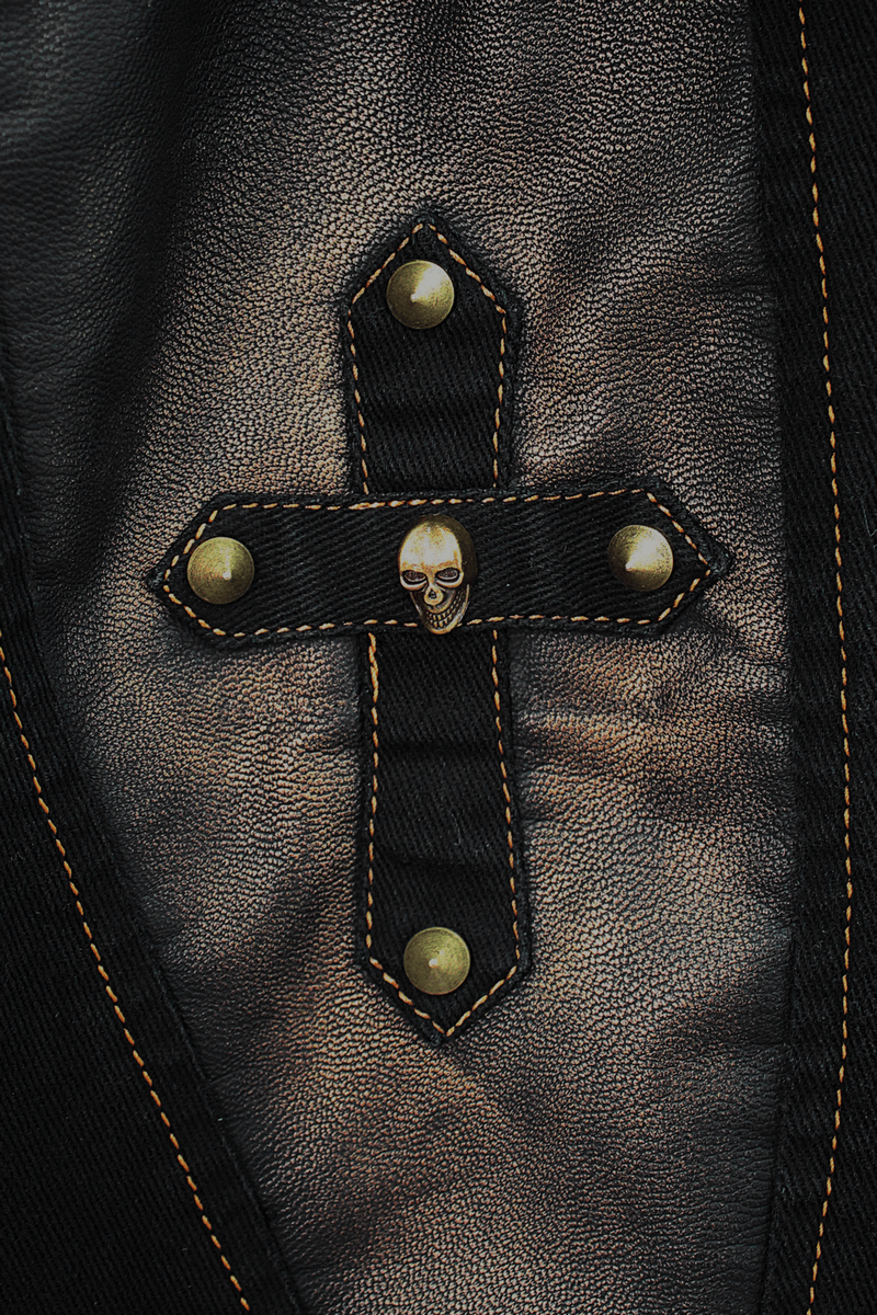 Close-up of a punk style cross patch with a skull and bronze rivets on black fabric, adding edgy flair to tight pants.