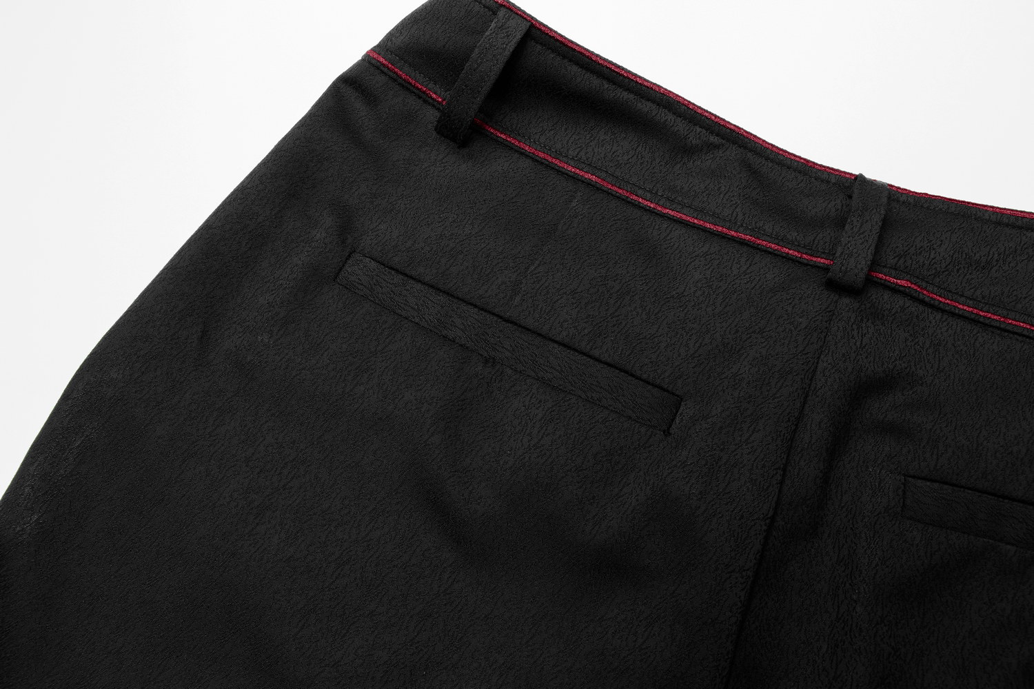 Close-up of men's tailored gothic trousers featuring bat embroidery and dark red stitching on back pockets.