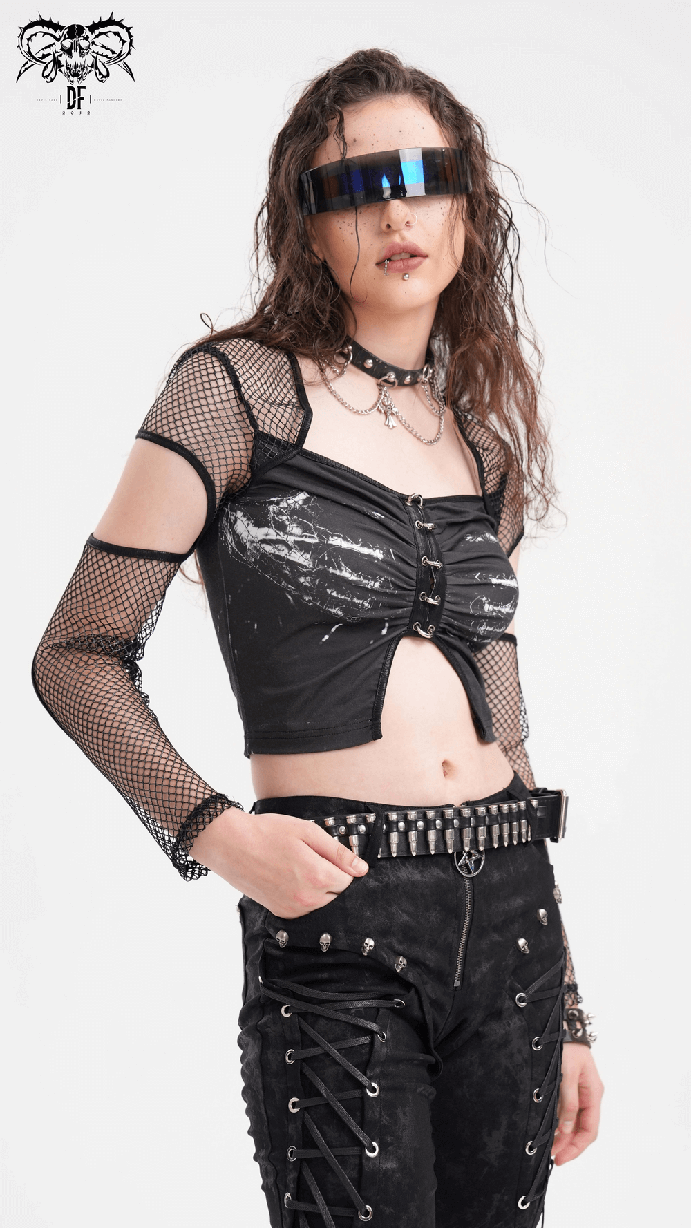 Edgy model wearing a black mesh long-sleeved crop top with cutouts and print, paired with stylish accessories and pants.