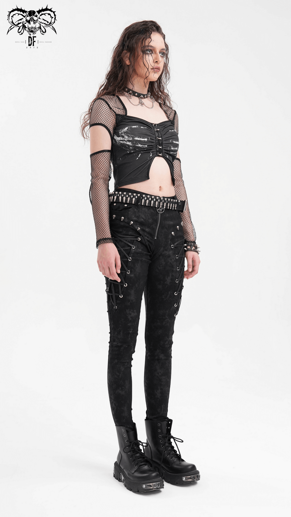 Edgy model in black mesh long sleeved crop top with cutouts, paired with studded high-waisted pants and chunky boots.