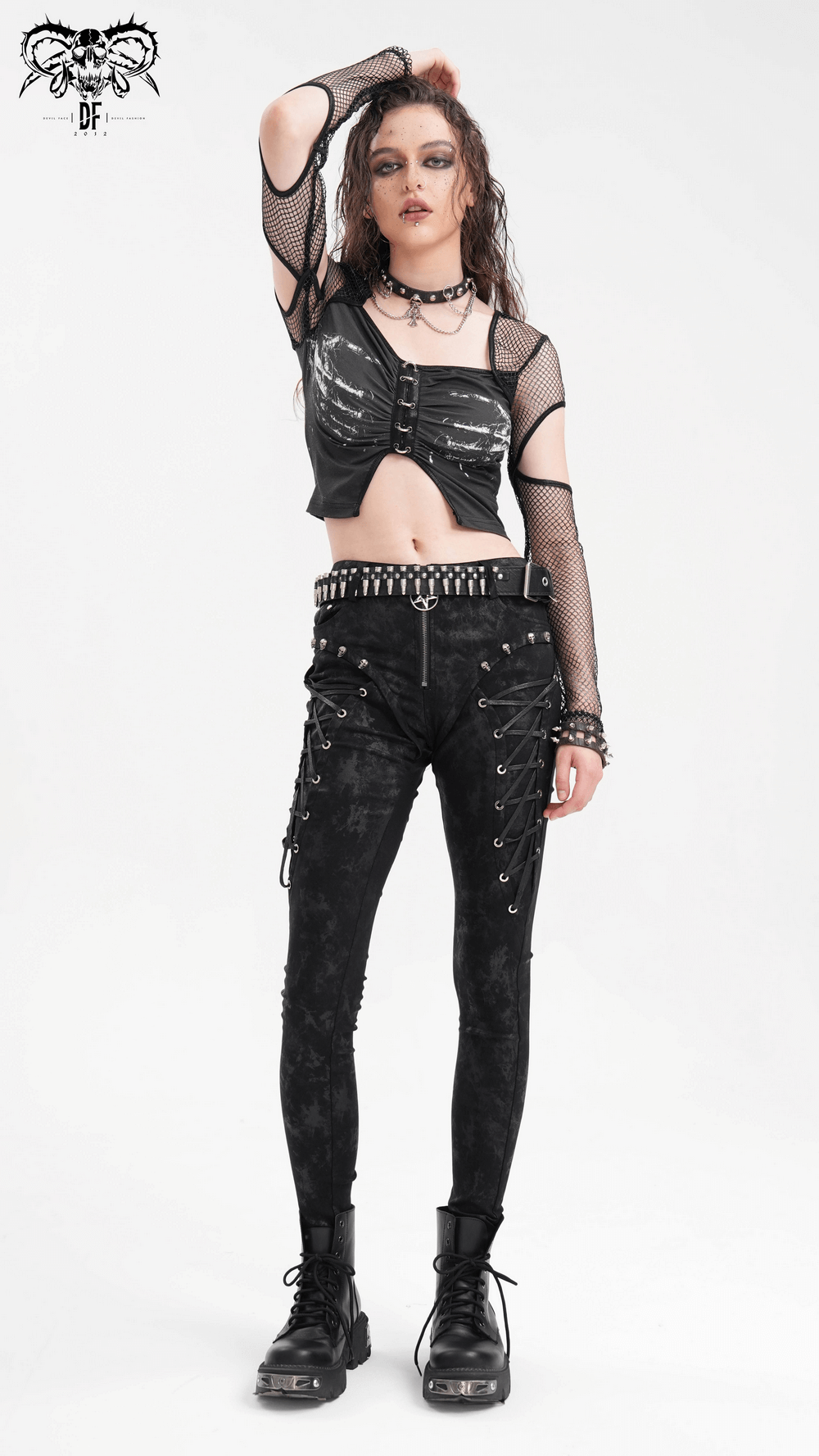 Edgy model in a black mesh long sleeved crop top with cutouts, paired with stylish black pants and combat boots.