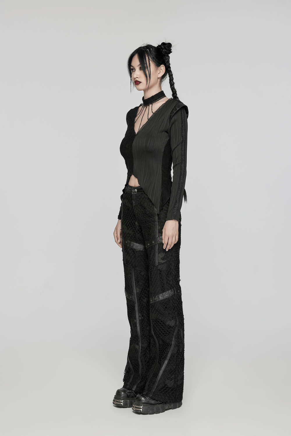 Edgy model in black mesh twill straight-leg pants with leather accents, showcasing modern fashion style.