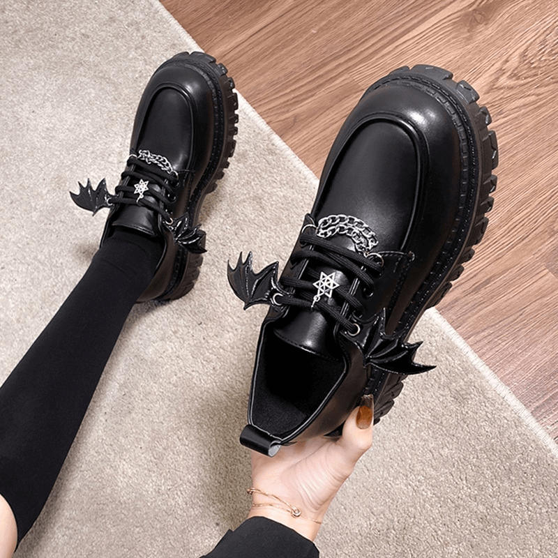 Chunky platform shoes with bat wings and metal chain accents, perfect for gothic style and edgy fashion.