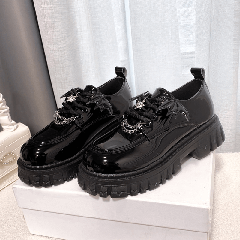 Metal chain bat wing chunky platform shoes in glossy black patent leather with round toes. Perfect for gothic outfits.