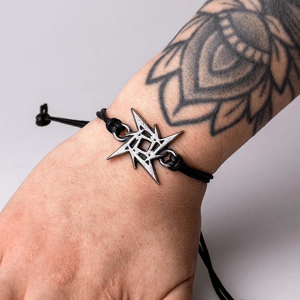 Metallica Ninja Star pewter bracelet on wrist, featuring black adjustable cord and intricate tattoo design.