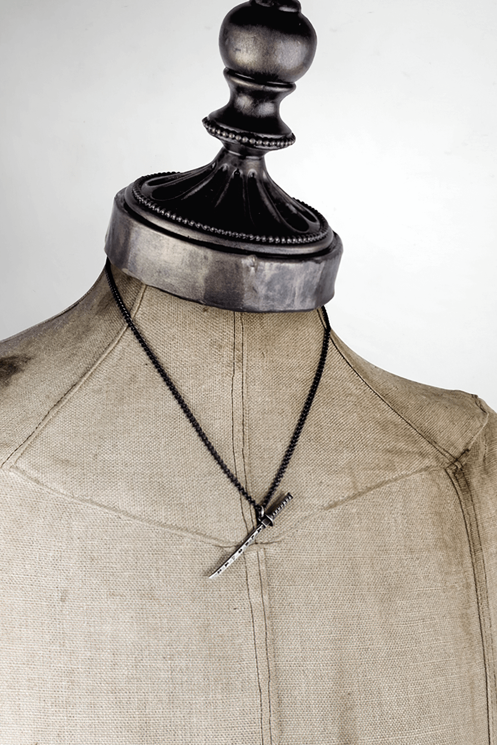Miniature samurai katana pendant displayed on a dress form, showcasing traditional Japanese jewelry craftsmanship.